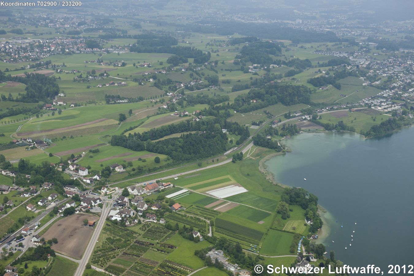Feldbach, im Vordergrund links; Verkehrskreisel, Bahnbrücke, Schulhaus. Siedlung im Hintergrund links: Hombrechtikon, am rechten Bildrand: Kempraten (Rapperswil)